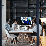 Four colleagues in a meeting room video conferencing.