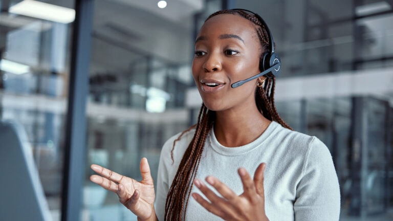 a person on phone through a headset in front of a computer