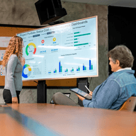 A woman presenting charts data ro a man