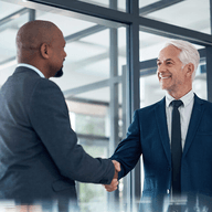 Two people wearing suites doing a hand shake
