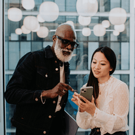 Two professionals reviewing smartphone content together