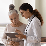 A doctor explaining something from a clipboard to an elderly woman
