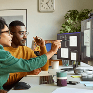 two colleagues analyzing data on monitor
